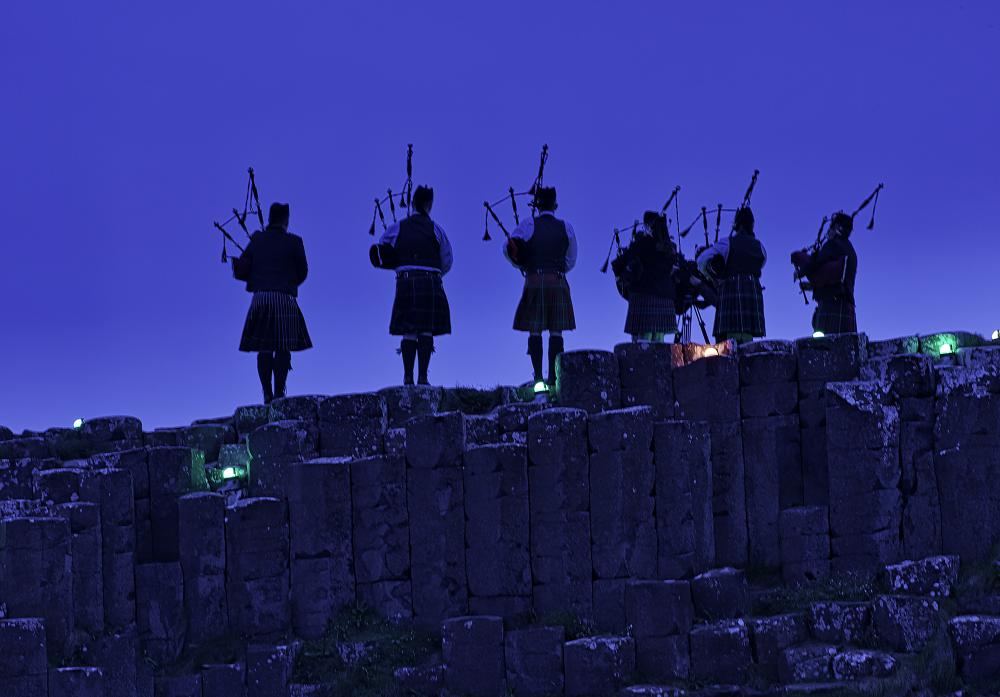 Bagpipers standing on a hill at dusk